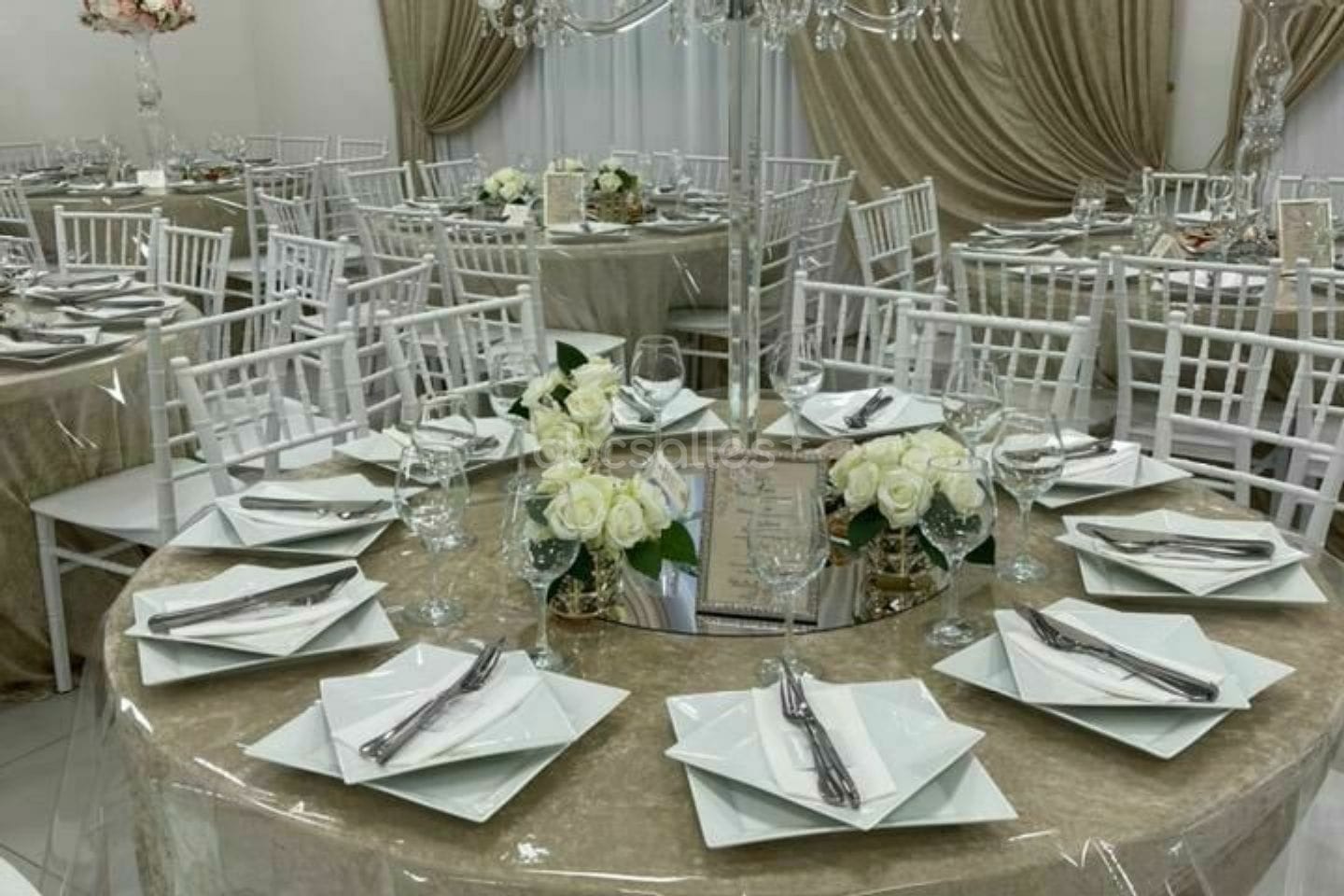 Table dressée, verres à pied et bouquet de roses blanches.