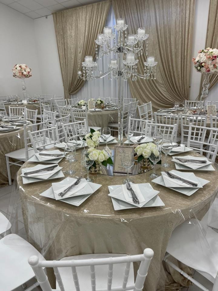 Table ronde avec chandelier de cristal et roses blanches.