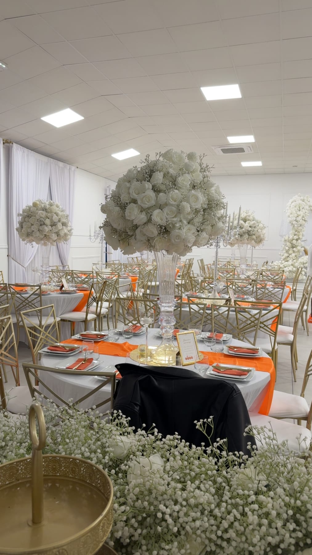 Grand bouquet de gypsophile au-dessus des tables, chaises dorées.